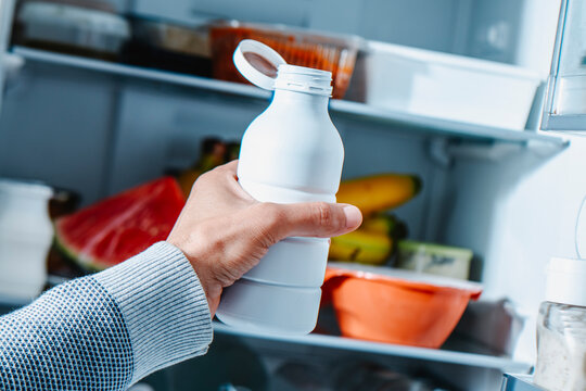a man pulls a drinkable yogurt from the fridge