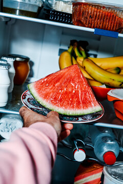 a man sets a plate with watermelon in the fridge