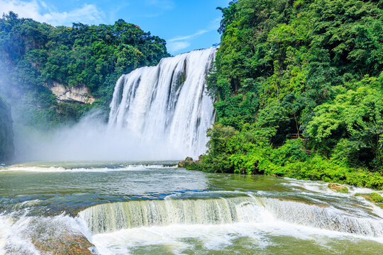 Powerful Huangguoshu Waterfall rushing into river basin in Anshun, China, with lush green vegetation