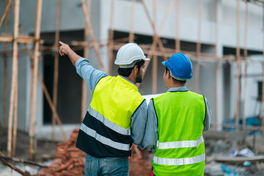 Construction worker team pointing scaffold site safety vest hard hat planning progress