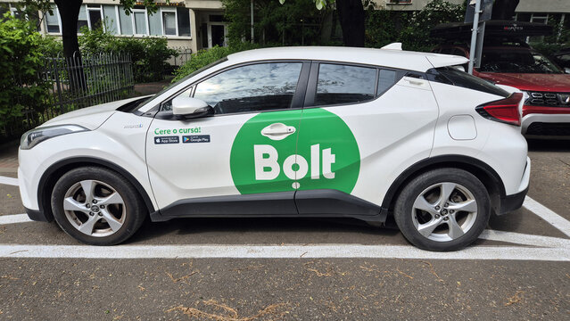 A white Toyota C-HR with green Bolt rideshare branding parked on a city street. Picture taken on April 29, 2026 in Bucharest, Romania.