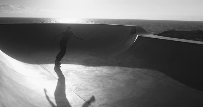 Boy having fun at skateboard park outdoor - Summer sunset, young person lifestyle and extreme sport concept - Black and white editing