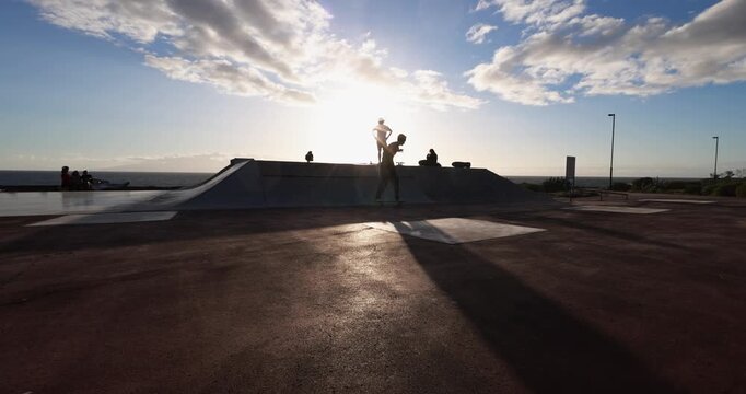 Teenager people having fun at skateboard park outdoor during sunset time - Summer lifestyle, skater boys and extreme sport concept