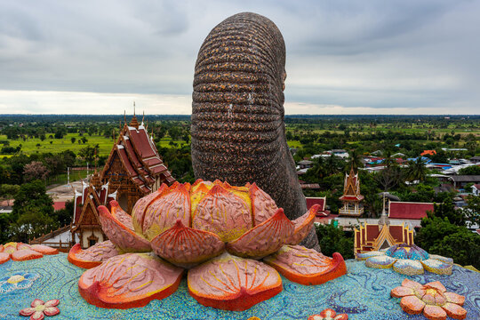 Wat Ban Rai temple in Korat, Thailand, with lotus sculpture and traditional Buddhist architecture. Panoramic view of rural landscape in background. Buddha statues and pagoda visible.
