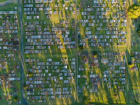 Overhead top down view of neat rows of graves in cemetery from aerial view