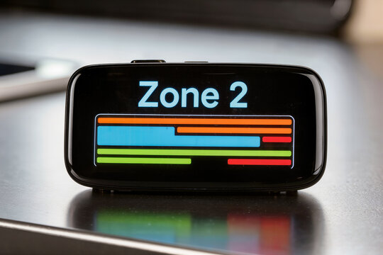 Fitness tracker display showing Zone 2 cardio training bars on dark desk