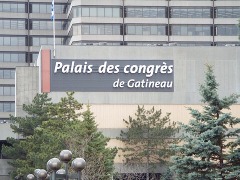 Gatineau, Quebec, Canada &ndash; March 10, 2026: The signage for the "Palais des congr&egrave;s de Gatineau" convention center is mounted on a large building behind evergreen trees on Bd Maisonneuve.