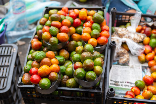 Fresh Organic Spondias Purpurea Fruit Displayed in Black Crates at an Outdoor Market