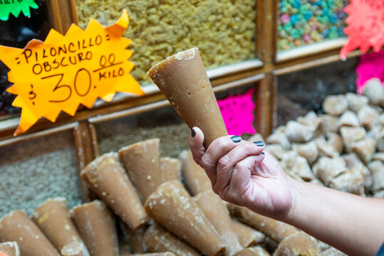 Detailed Close Up of Hand Holding Dark Piloncillo Cones with Price Tag in a Market