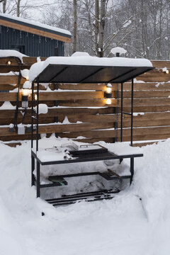 Outdoor cooking area covered in snow representing seasonal pause. Concept of winter dormancy and cozy backyard atmosphere with festive lights