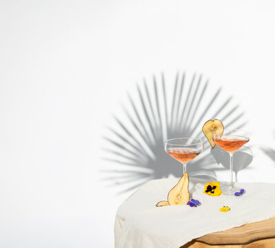 Two rose wine glasses with summer cocktails and dried fruit appetizers
