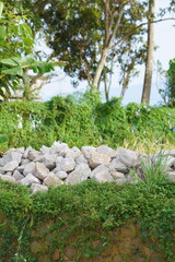 Fototapeta premium Pile of rough grey stones on a grassy slope in a garden