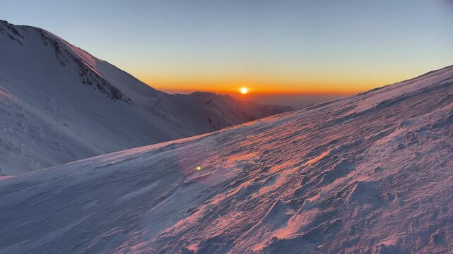 Summit push day beginning with incredible sunrise during Extreme expedition under famous Lenin peak (Ibn Sina Peak) 7134m. High altitude view with icy slope deep snow over clouds landscape.
