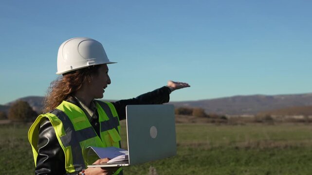 Engineer architect planning woman discussing project specifications on laptop outdoors at construction site land.