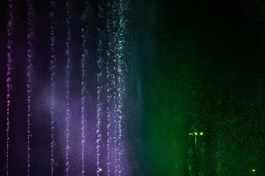 fountain background, water jets of a multi-colored fountain changing color on a black background, musical fountain
