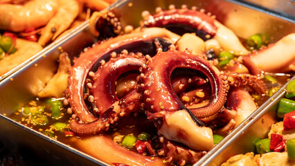 A variety of marinated seafood, including snails, crab claws, and octopus tentacles, seasoned with spicy chili and herbs. © JUN LI