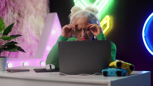 Eccentric grandma in a headset playing on a laptop, upset after losing the game