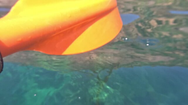 Kayaking paddle rowing through crystal clear turquoise water during an active summer vacation outdoor adventure