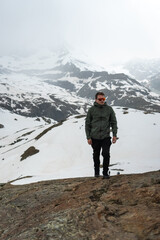 Fototapeta premium Man hiking rocky terrain with snow-capped mountain backdrop