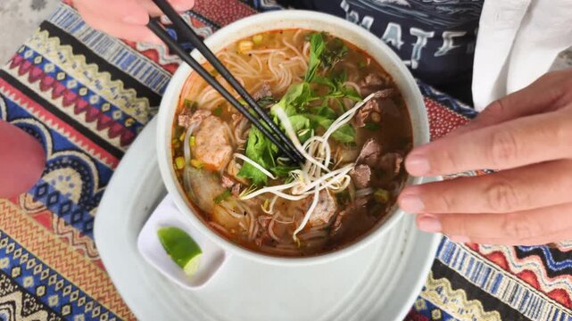 Fresh garnish for soup features hands adding green herbs and bean sprouts to hot broth. Vibrant mint and cilantro enhance aromatic Vietnamese noodle bowl. This fresh garnish for soup adds.