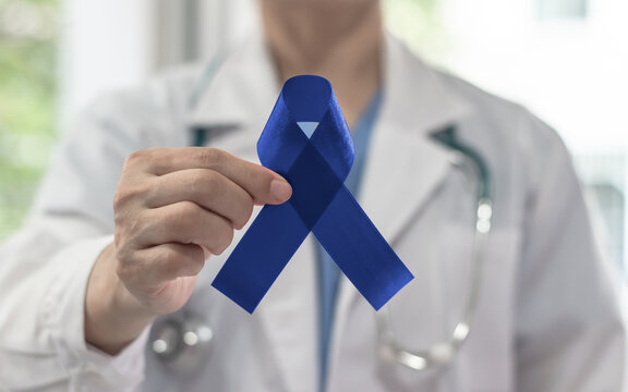 Dark blue ribbon for colon and colorectal cancer awareness month, Acute Respiratory Distress Syndrome (ARDS), Alopecia, Arthritis, Tuberous Sclerosis, Guillain Barre Syndrome bow on doctor's hand