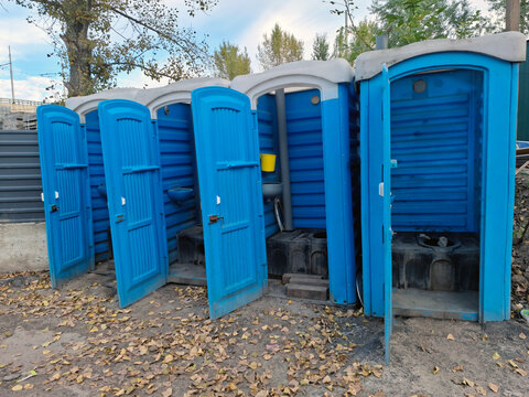 The blue plastic toilet cabins have open doors for ventilation