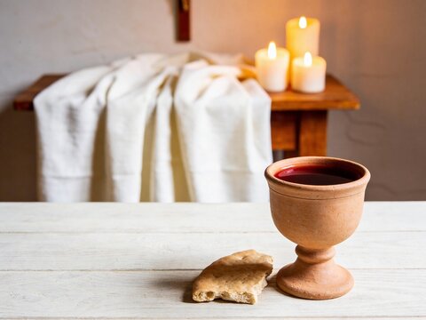 Complete rustic clay chalice of wine and broken unleavened bread with white linen copy space