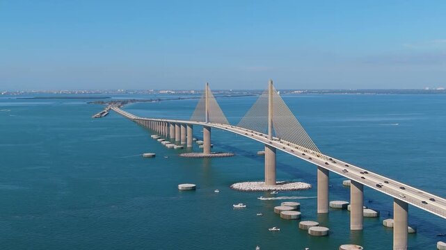 Cinematic drone shot of the iconic Sunshine Skyway Bridge spanning the turquoise waters of Tampa Bay on a bright, sunny day.