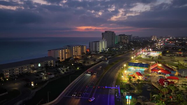 Cinematic nighttime drone shot of the illuminated hotel strip and neon lights along the Panama City Beach coastline.