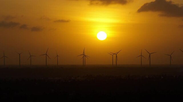Ilha do Guajiru Itarema Cear&aacute; Brazil shows onshore wind farm with utility scale turbines on coastal plain near Atlantic shoreline and kitesurf lagoon formed by sand peninsula, aerial drone static shot