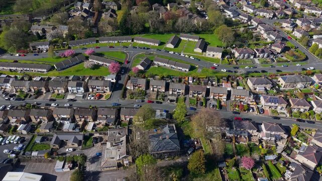 A drone flies along Princes Drive in Skipton towards the Skipton Building Society headquarters, revealing bungalows, terraced houses, spring blossom trees and surrounding roads. North Yorkshire.