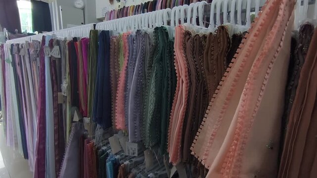 Colorful square hijabs hang neatly on display hangers. These popular headscarves are ready for sale. They are a high-demand fashion choice for Muslim women.