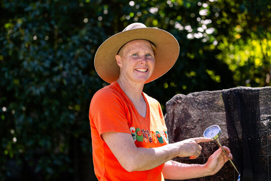 Female environmentalist checking temperature gauge on backyard compost pile