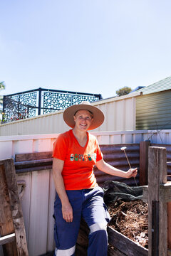 woman with backyard garden compost pile by colorbond fence