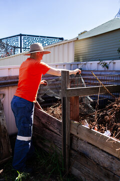 woman with backyard garden compost pile by colorbond fence