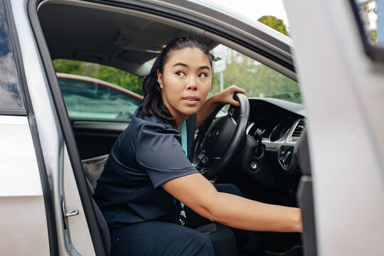 Driver opening the car door and turning to check surroundings while seated in car