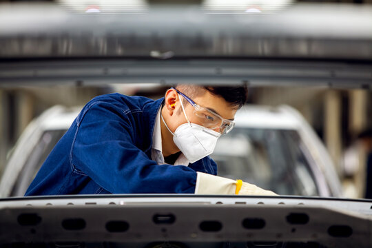 Asian workers are working on a car assembly line.