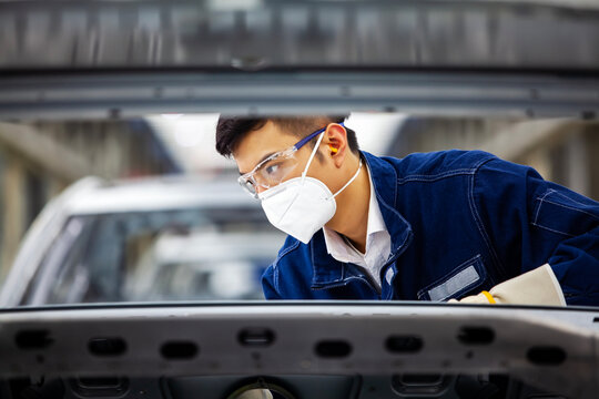 Asian workers are working on a car assembly line.