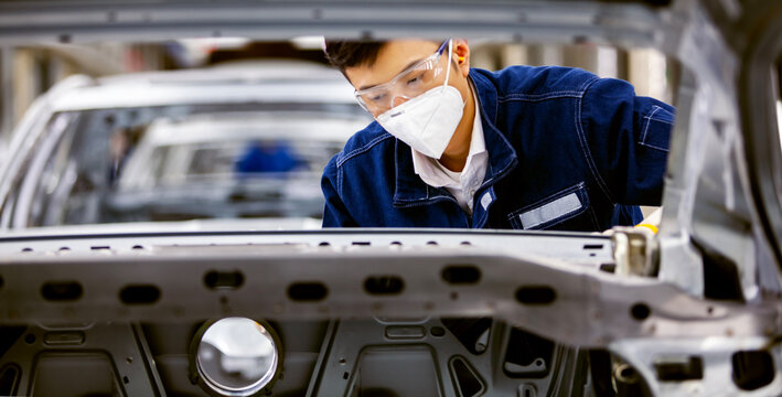 Asian workers are working on a car assembly line.