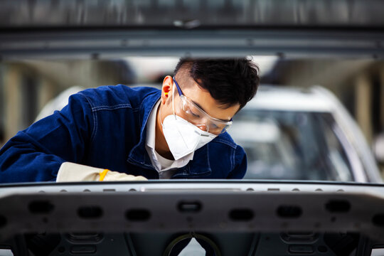 Asian workers are working on a car assembly line.