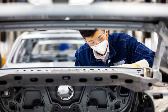 Asian workers are working on a car assembly line.