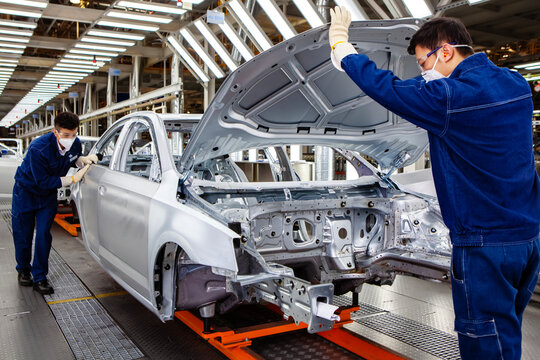 Two Asian workers are working on a car production line.