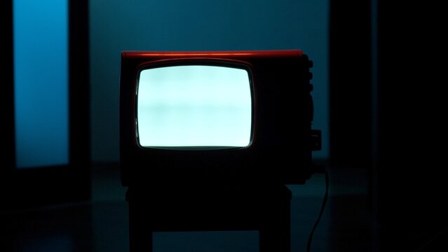 Retro crt television glowing with static in a dim room, evoking vintage analog technology, media nostalgia, and quiet obsolescence of past electronic entertainment