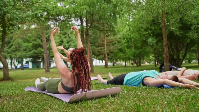 Group of women doing abs exercises on grass mats outdoors together during summer fitness class. Abs exercises, mats, group, fitness, outdoors, women.