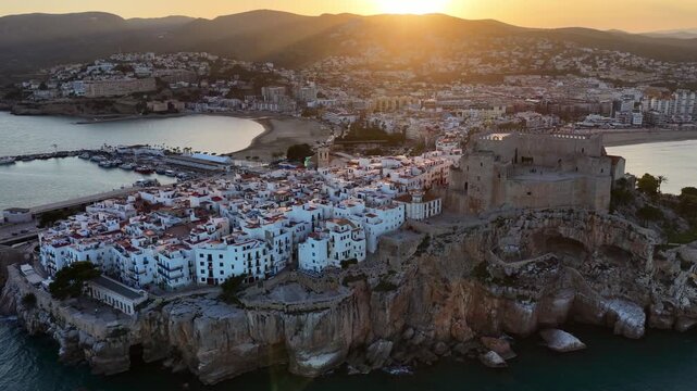 Sunset orbiting drone view of Peniscola, Valencia Provence, Spain, historic resort town of Peniscola with a fortress and a castle in the Mediterranean, holiday destination in Spain