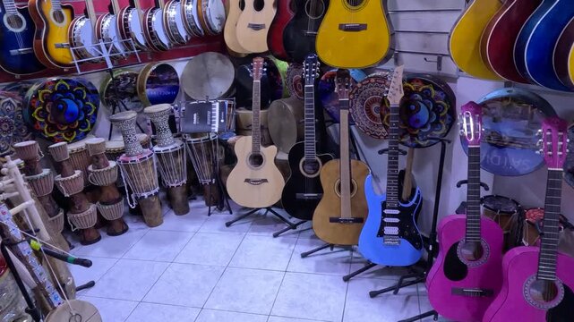 Interior of a musical instrument shop filled with guitars, banjos, and drums. A vibrant display of modern and traditional instruments arranged on walls, shelves, and stands in a music store.