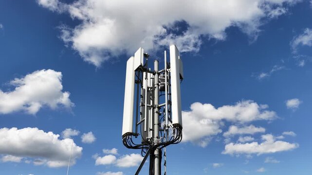 Modern cellular network antenna for 5g and lte data transmission against a bright blue sky with white clouds, representing global connectivity, communication technology, and wireless infrastructure