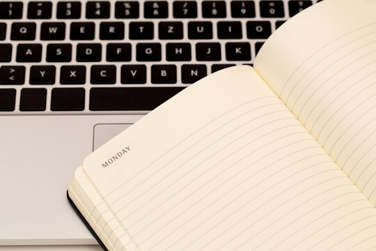 Notebook open on a desk next to a laptop showing the start of a new week