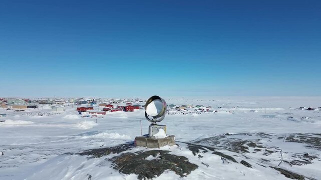 A close-up aerial pan of a rusted, abandoned parabolic communications dish on a rocky hilltop in Rankin Inlet (Kangiqliniq), traditionally used for maritime and remote Arctic telecommunications.