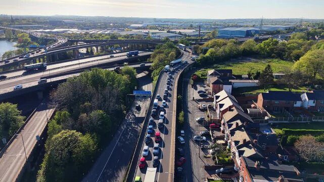 Forward aerial drone footage flying above moving traffic on a motorway exit ramp at a complex highway interchange in Birmingham, UK.